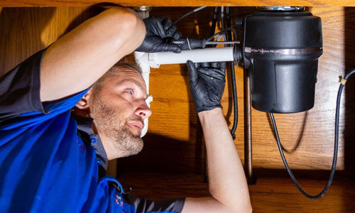 man fixing pipes underneath a sink