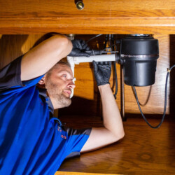 man fixing pipes underneath a sink